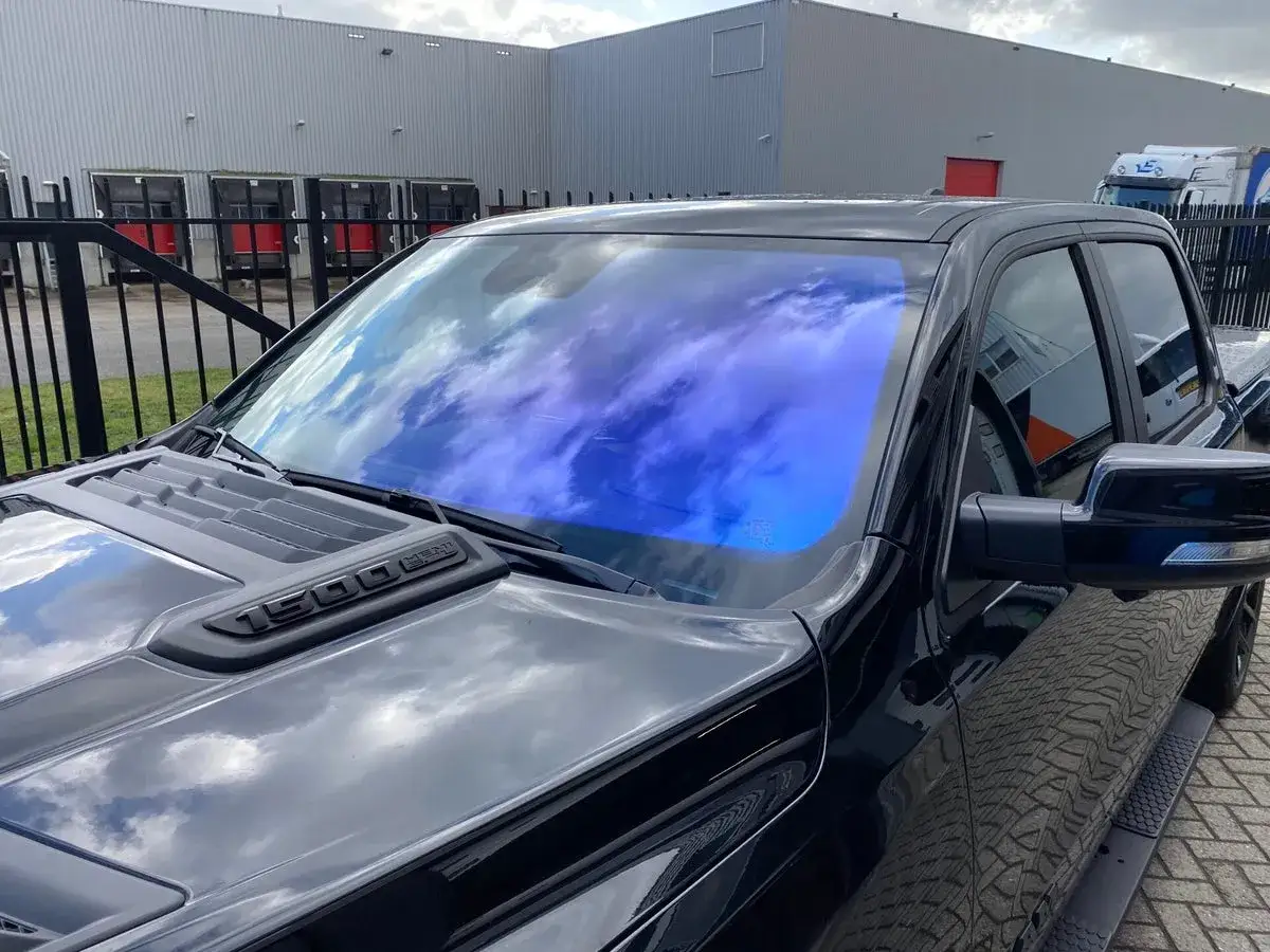 Schwarzer Pickup mit blauer Windschutzscheibenfolie, die den Himmel reflektiert. Scheinwerfer folieren erlaubt, um diesen Look zu erzielen.