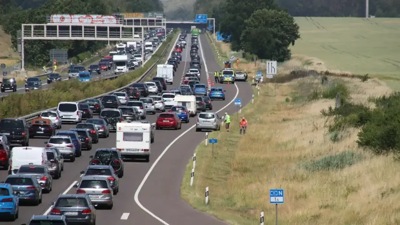 Langer Stau auf der A11. Viele Autos stehen auf der Autobahn, einige mit Wohnwagen. Polizei regelt den Verkehr.