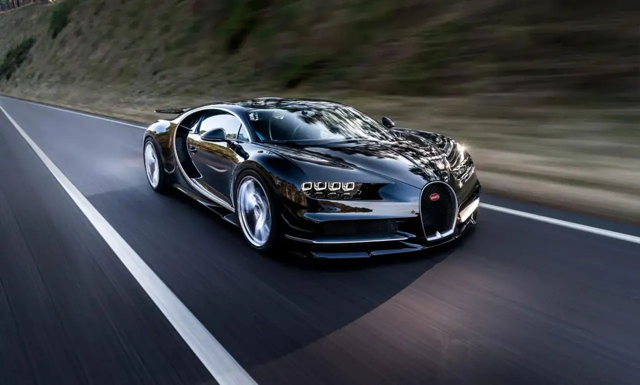 Schwarzer Bugatti Chiron rast auf der Stra&szlig;e, ein Symbol f&uuml;r Geschwindigkeit und die Jagd nach dem Bugatti Chiron 0-400 Rekord.