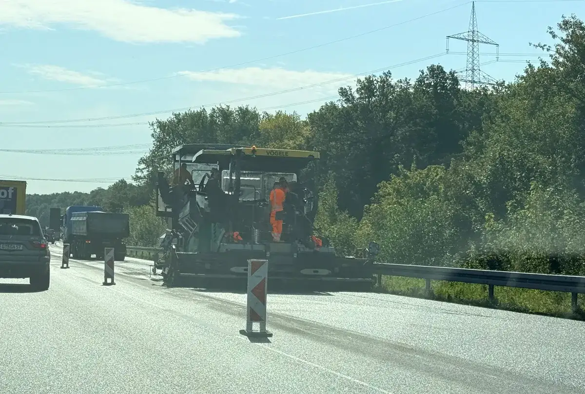 Straßenbauarbeiten auf der A30 sorgen für einen zähen stau. Ein Asphaltfertiger legt neuen Belag.