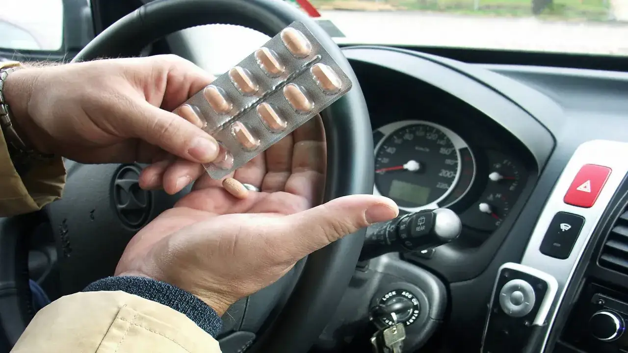 Mann nimmt Medikamente im Auto ein, um sicher autofahren zu k&ouml;nnen.