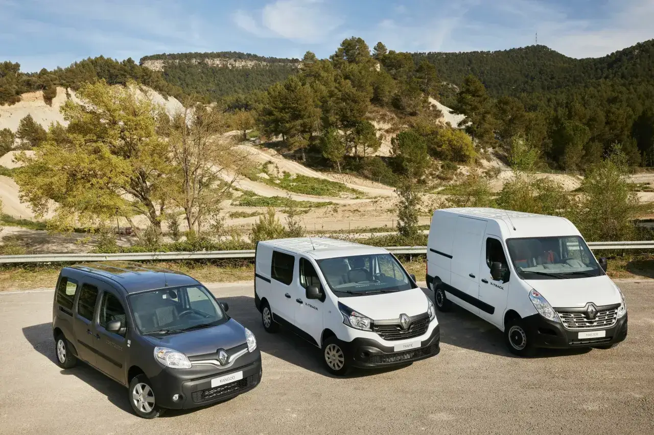 Drei Renault Kastenwagen Modelle: Kangoo, Trafic und Master, stehen in einer bergigen Landschaft.