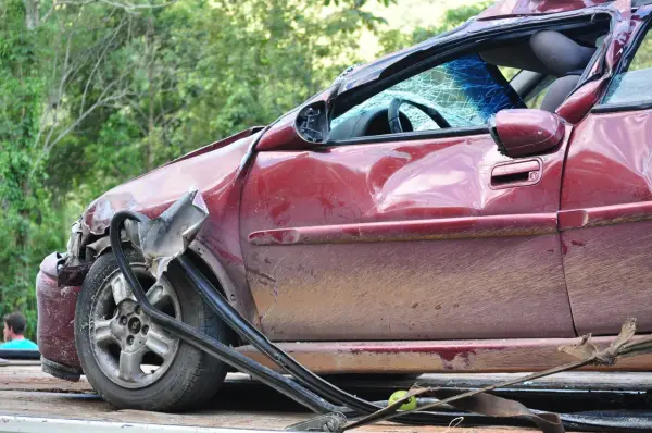 Schwer beschädigter roter Wagen, Windschutzscheibe zerbrochen. Ein trauriges Zeugnis eines Unfalls, vielleicht durch Alkohol verursacht.