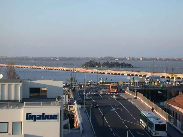 Autobahn nach Venedig mit dem Auto. Eine lange Brücke überspannt das Wasser, Autos und Busse fahren auf der Straße.